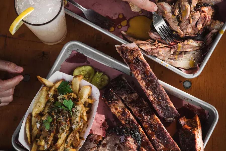 Overhead shot of two plates filled with barbecued meats and sides.