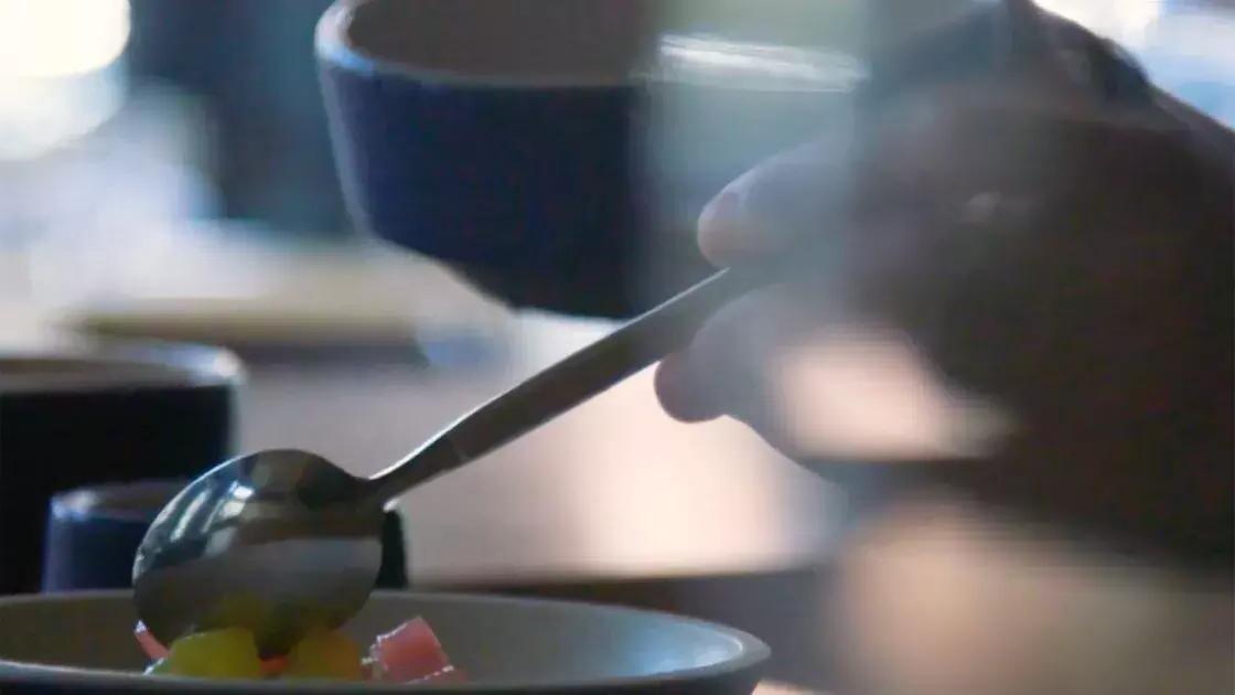 A ladle pours sauce over a plate of food.